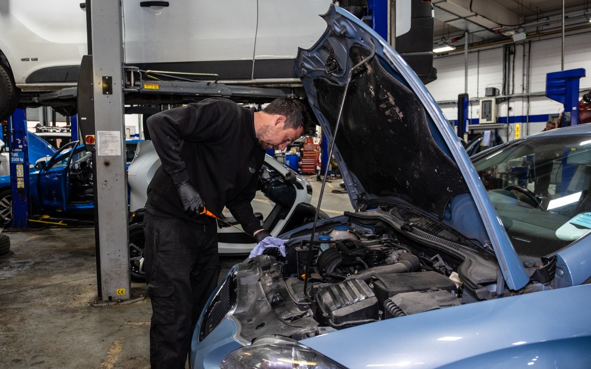 A technician performs an oil check as part of a car service