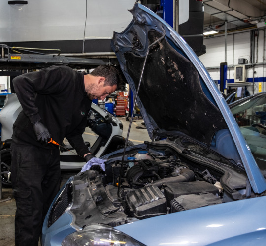 A technician performs an oil check as part of a car service