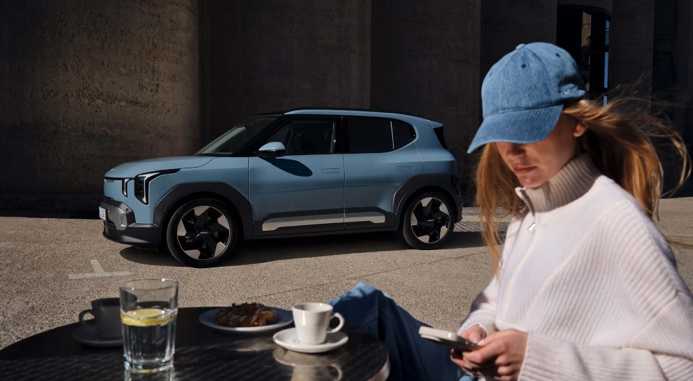 A person sat relaxing next to The Kia EV2 new vehicle; The Kia EV2 new car models