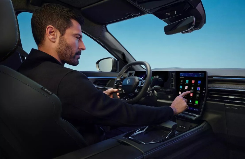 The driver of a Renault Austral is selecting an icon on the infotainment touchscreen.
