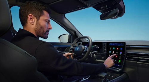 The driver of a Renault Austral is selecting an icon on the infotainment touchscreen.