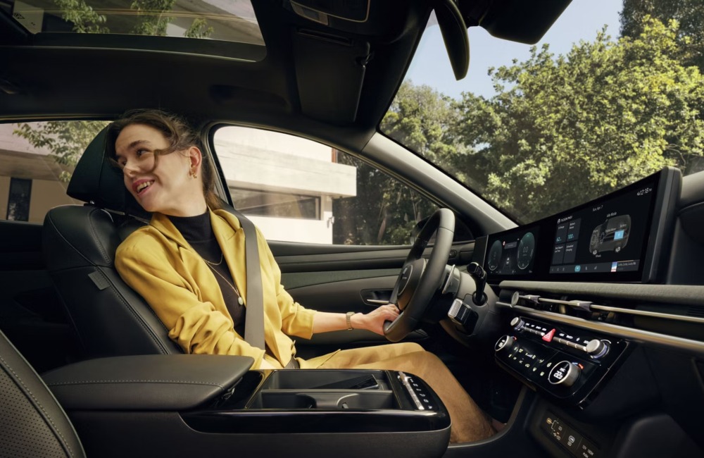 A person sat in the drivers seat of a new Hyundai TUCSON, looking into the rear seats happily.