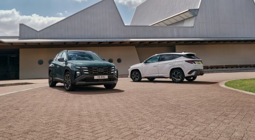 Two Hyundai TUCSON Hybrid cars parked next to one another, with focus on the front and rear designs on the vehicles.