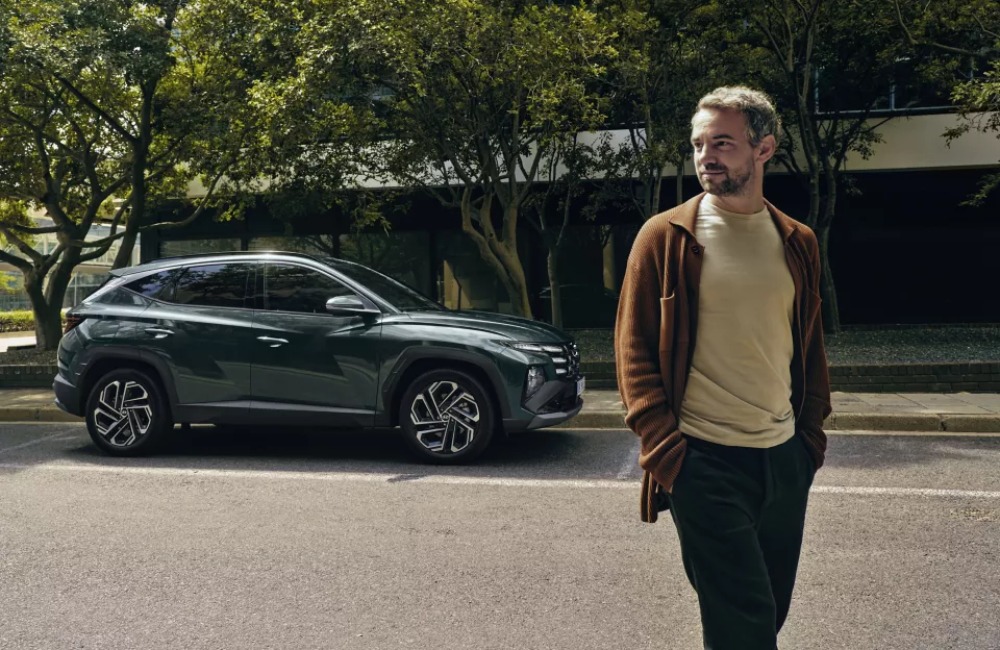 A person walking away from a parked Hyundai TUCSON Hybrid.