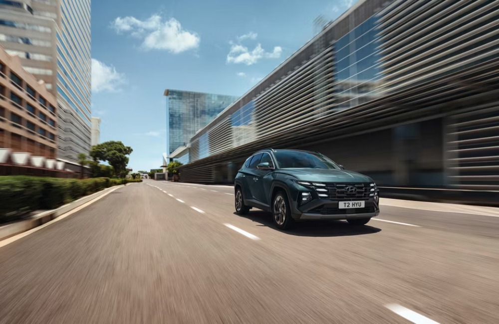 A new Hyundai TUCSON Hybrid driving down an empty city street at speed.
