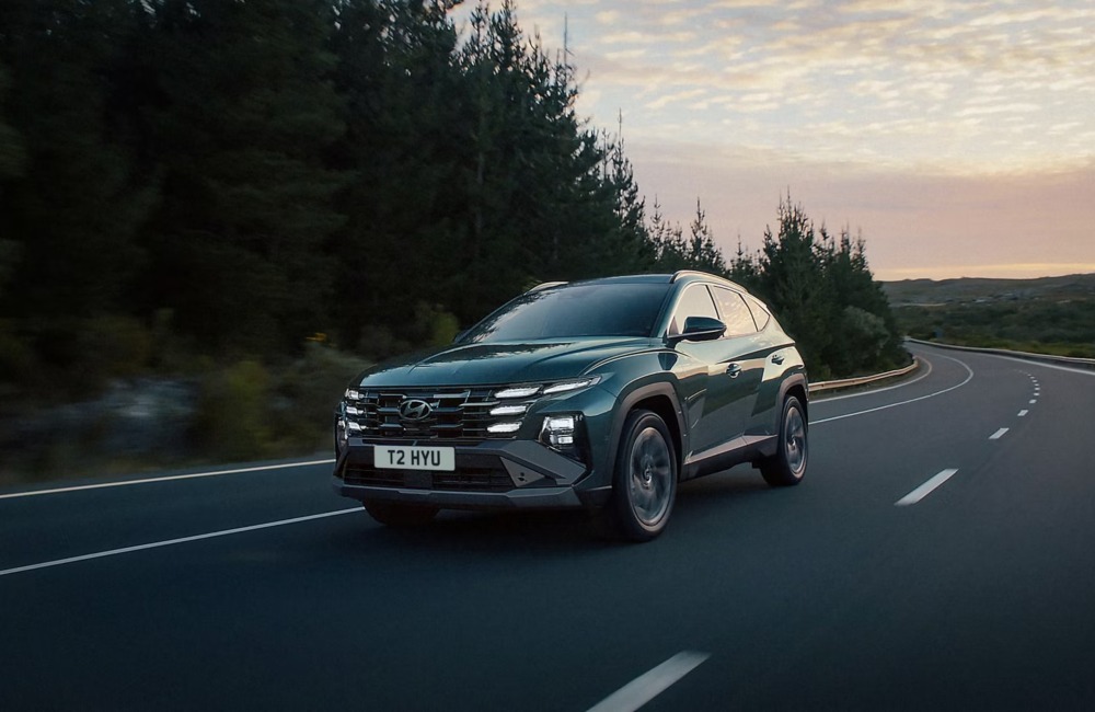 New Hyundai TUCSON Plug-in Hybrid driving down a mountainous country side road at speed.