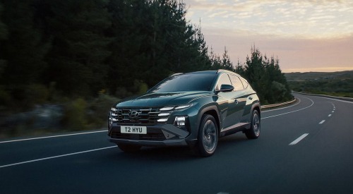 New Hyundai TUCSON Plug-in Hybrid driving down a mountainous country side road at speed.