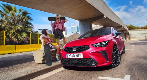 Two people with skateboards posing next to a new SEAT Ibiza which is parked on an urban street