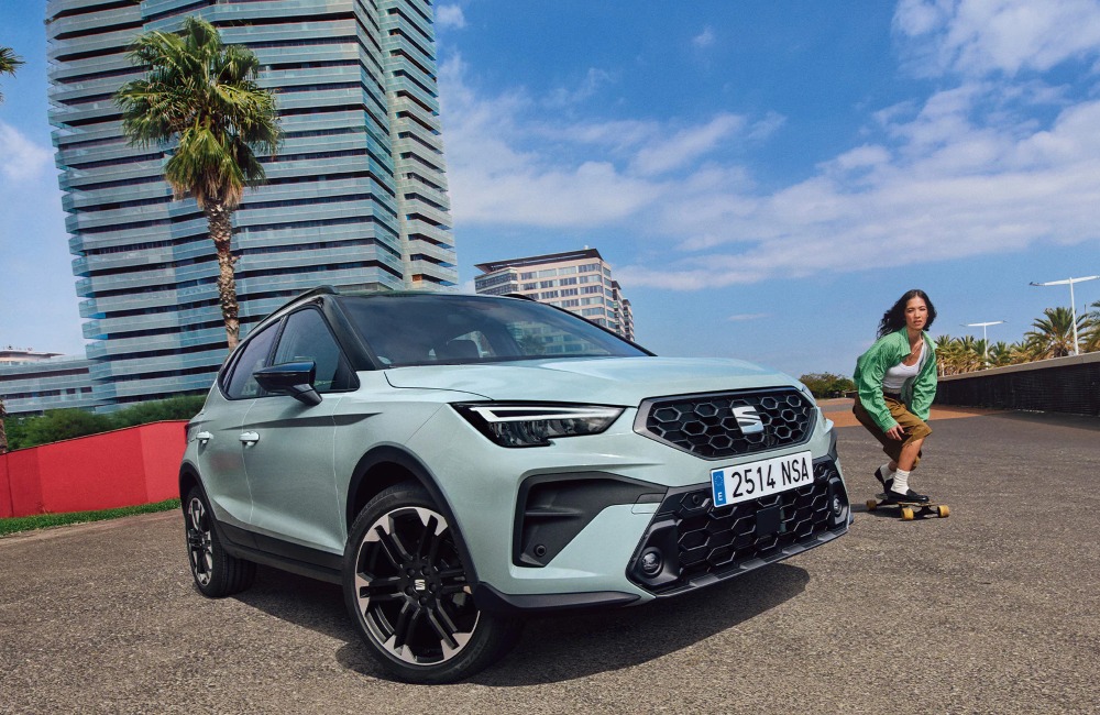 Angled front shot of a new SEAT Arona, with a person skateboarding past.
