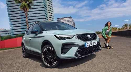 Angled front shot of a new SEAT Arona, with a person skateboarding past.