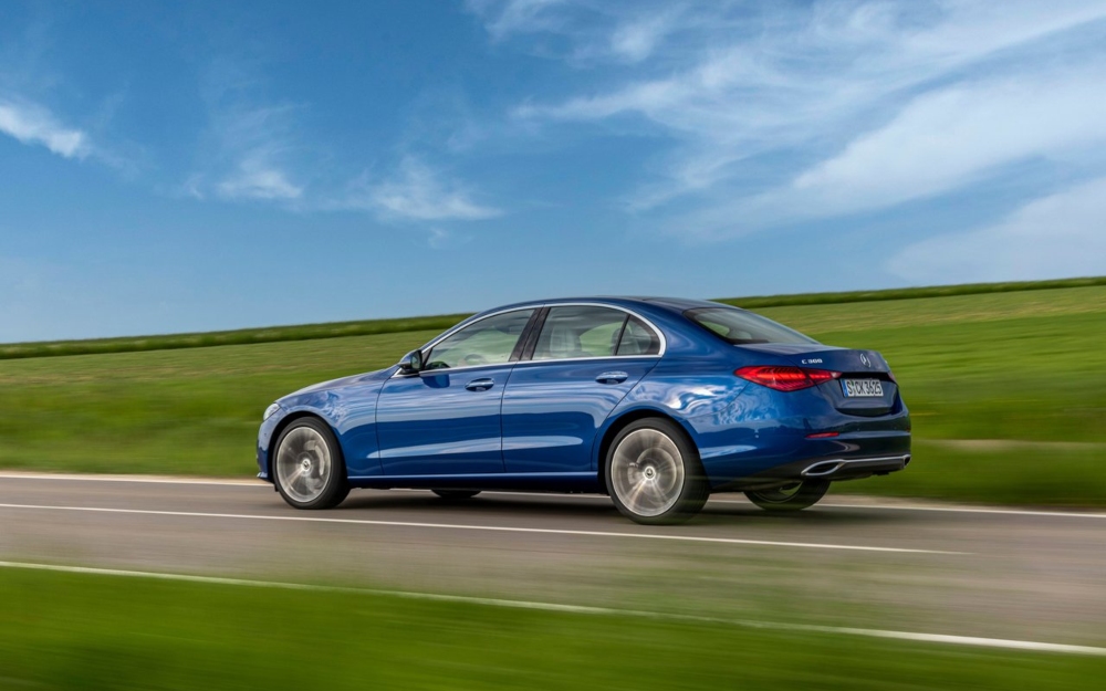 Used Mercedes-Benz C-Class in blue driving on a road in sunny conditions.