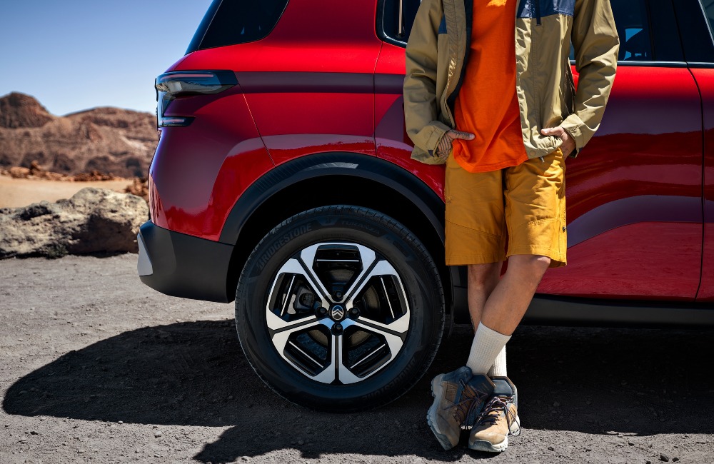 Person leaning on a new Citroen C3 Aircross, the shot only includes the bottom half of the person as it shows off the cars alloy wheels and bold design.