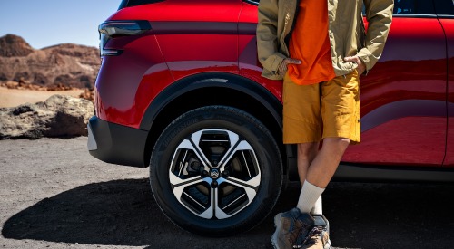 Person leaning on a new Citroen C3 Aircross, the shot only includes the bottom half of the person as it shows off the cars alloy wheels and bold design.