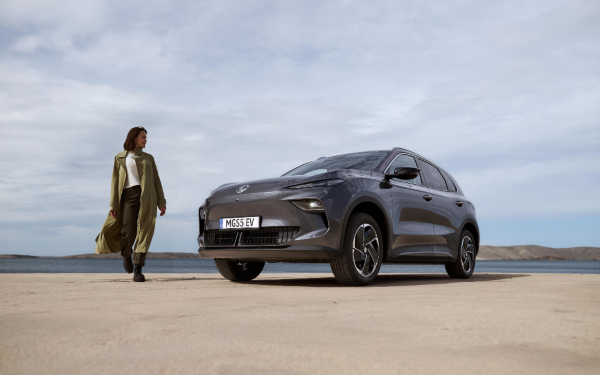Used MGS5 EV in Camden Grey MGS5 EV in Camden Grey on sand with a woman walking beside it.
