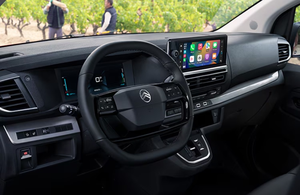 Interior shot of the drivers wheel, infotainment system, digital clusters, and centre console of a used Citroen Dispatch.