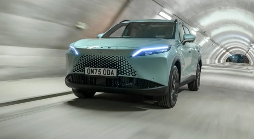 Front angled view of a new OMODA 7 going at speed down a lit tunnel, with a focus on the front LED lights and unique grille.