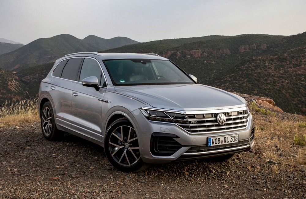 Angled front shot of a Volkswagen Touareg parked at the peak of a hill, surrounded by other mountainous terrain.