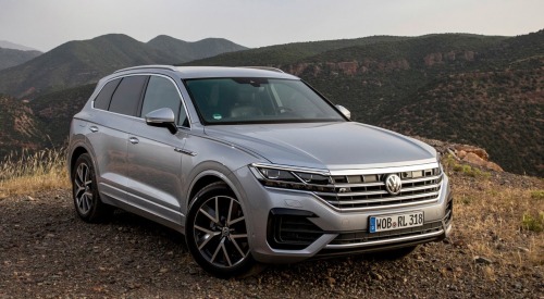 Angled front shot of a Volkswagen Touareg parked at the peak of a hill, surrounded by other mountainous terrain.