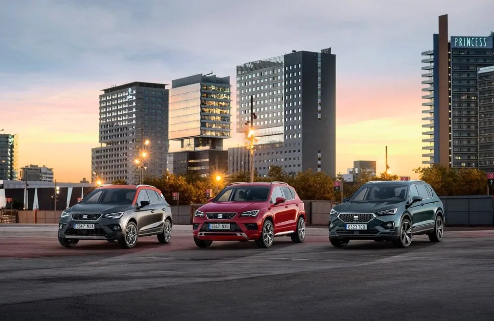 Three used SEAT cars lined up next to one another. They are posing infront of a sunset cityscape, with the focus being on the cars unique front design.