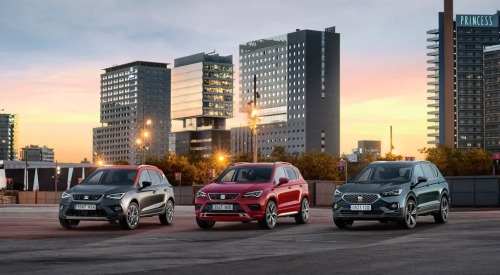 Three used SEAT cars lined up next to one another. They are posing infront of a sunset cityscape, with the focus being on the cars unique front design.