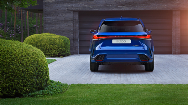 Rear view of the new Lexus RX 500h by a garage