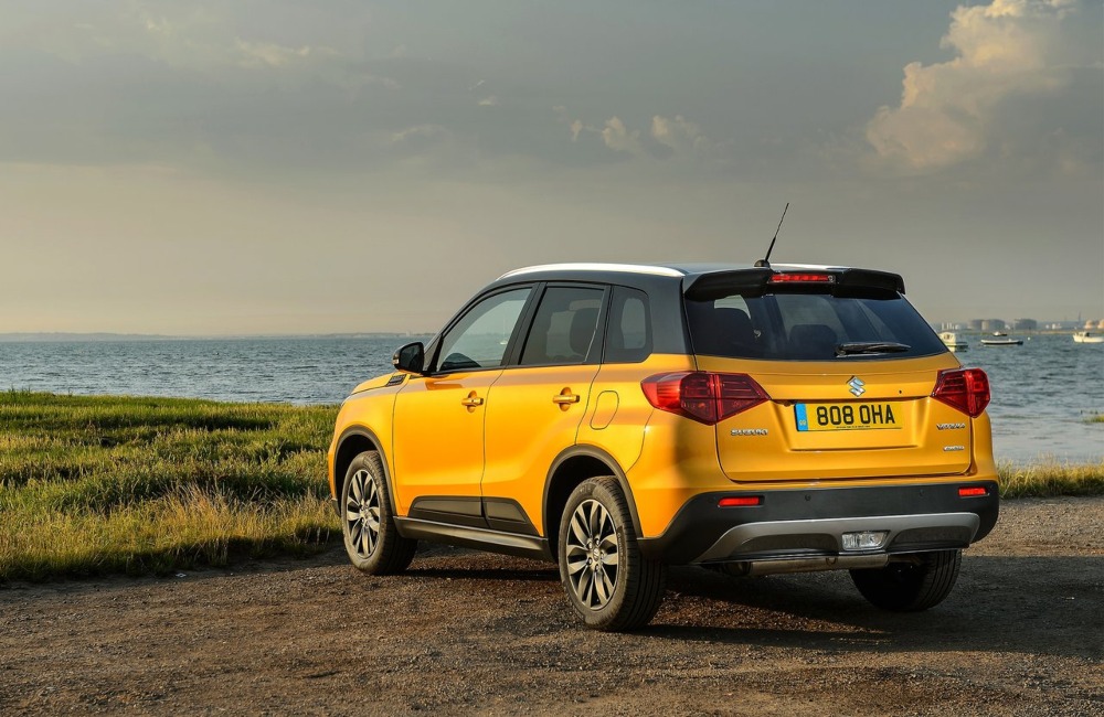 Angled rear shot of a used Suzuki Vitara parked on a cliff overlooking the ocean.
