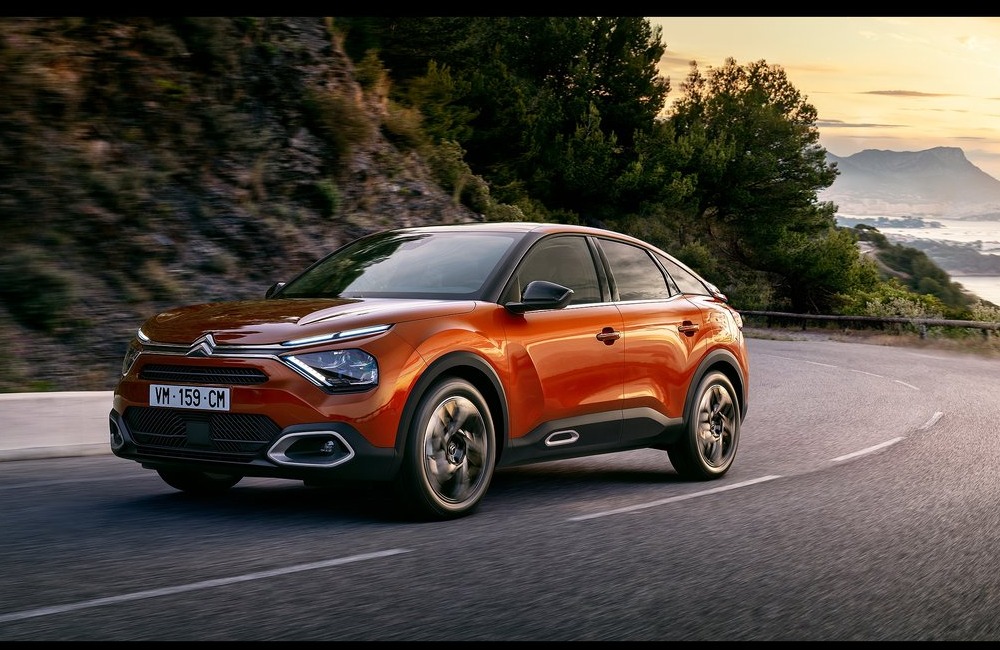 Front angled side shot of a Citroen C4 driving at speed down a scenic cliff-side road.
