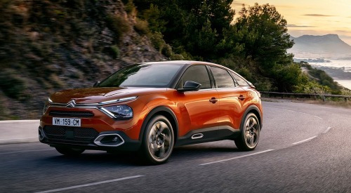 Front angled side shot of a Citroen C4 driving at speed down a scenic cliff-side road.