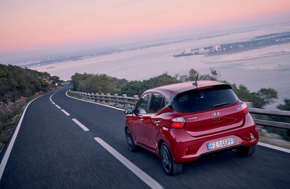 Rear shot of a used Hyundai i10 driving at speed down a cliffside road.