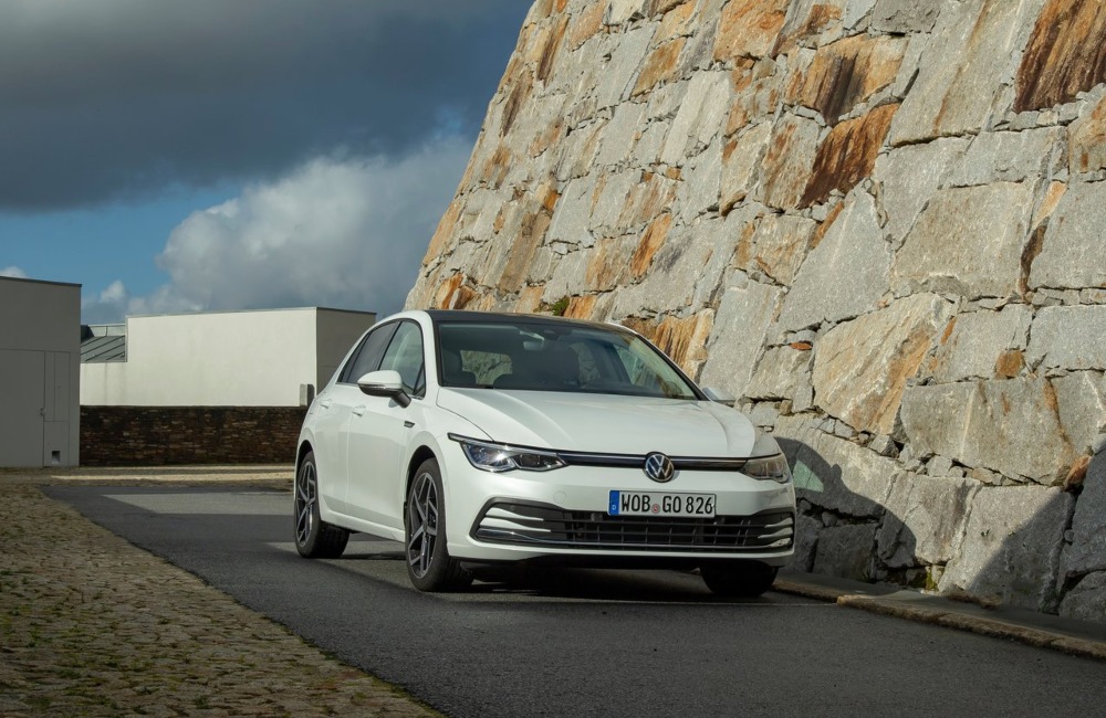 VW Golf parked on a road next to a rock side.