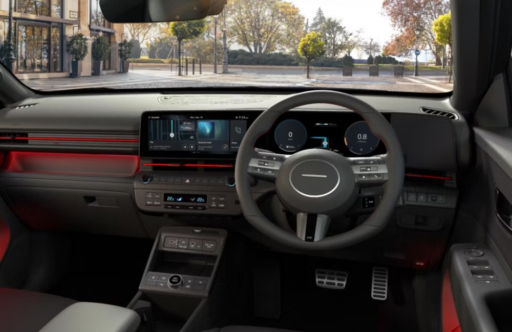 A shot of the new Hyundai KONA interior, showing off the driving position, infotainment system, centre console, steering wheel, and interior lighting.