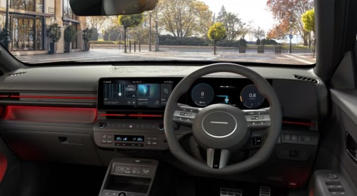 A shot of the new Hyundai KONA interior, showing off the driving position, infotainment system, centre console, steering wheel, and interior lighting.
