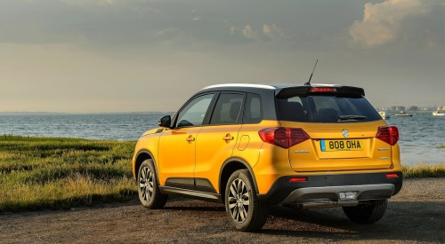 Angled rear shot of a used Suzuki Vitara parked on a cliffside overlooking the ocean.