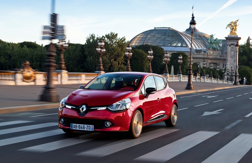 Angled front shot of a used Renault Clio driving at speed down a town street.