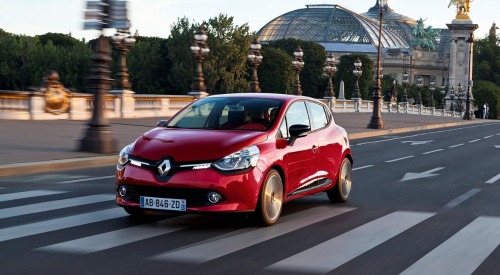 Angled front shot of a used Renault Clio driving at speed down a town street.
