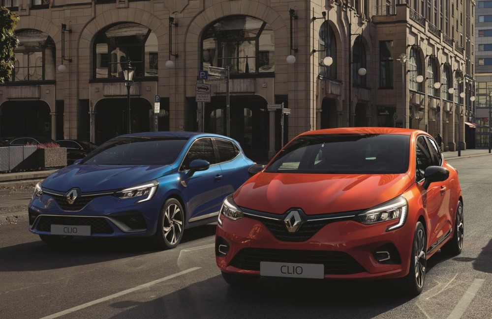 Two used Renault Clio cars parked next to one another on a town road.