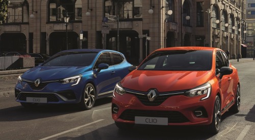 Two used Renault Clio cars parked next to one another on a town road.