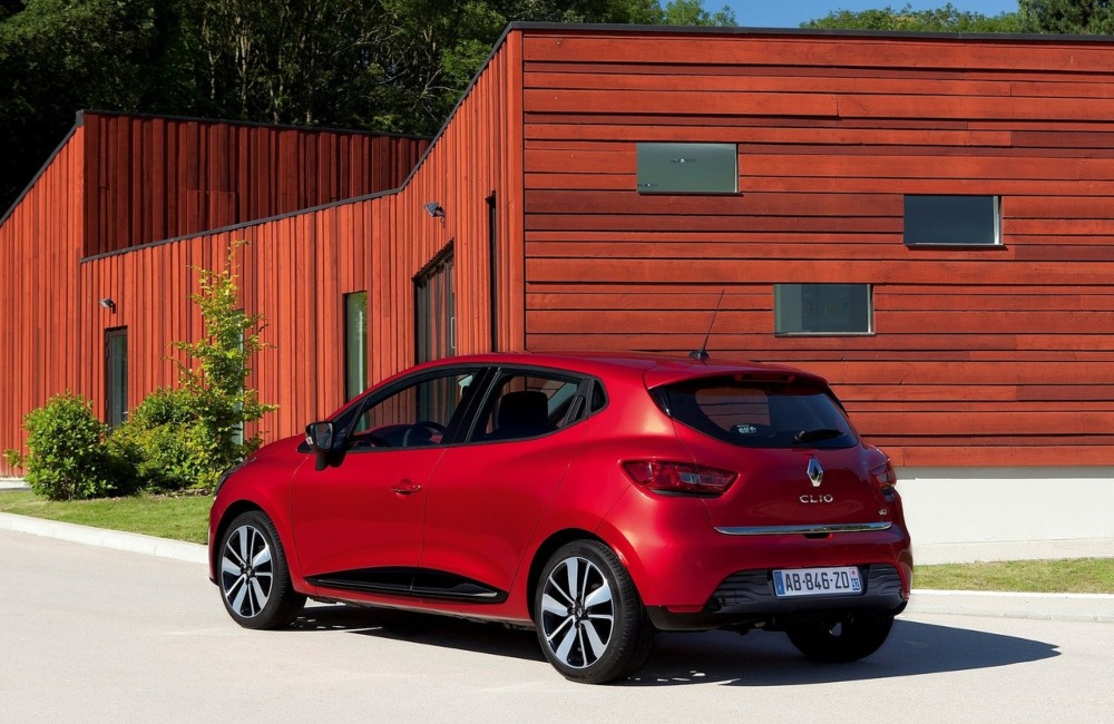Rear angled shot of a used Renault Clio parked in front of a wooden panel house.