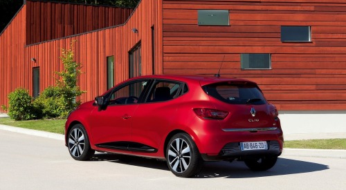 Rear angled shot of a used Renault Clio parked in front of a wooden panel house.