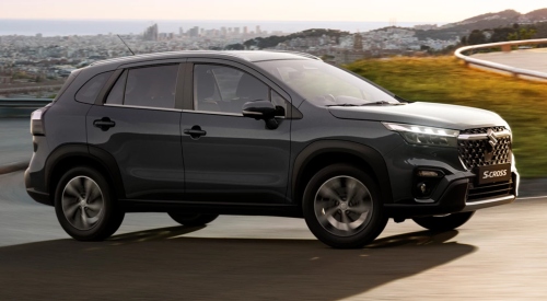 Angled side shot of a new Suzuki S-Cross driving up a windy countryside road at speed.
