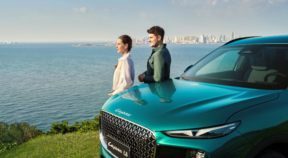 Two people leaning on a LEPAS L8 in Expressive Emerald overlooking the sea; New LEPAS Plug-in Hybrid