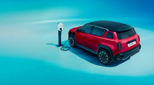 A red new Renault 4 Plein Sud charging up at a charging station. The backdrop is blue.