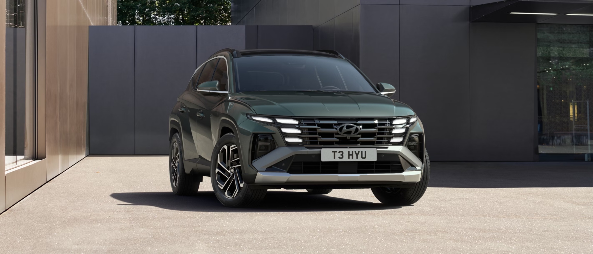 Front shot of a new Hyundai TUCSON parked in front of a modern house, showing off the LED lighting and new design.