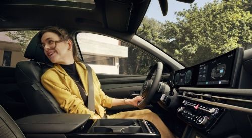 A person sat in the drivers seat of a new Hyundai TUCSON, looking into the rear seats happily.