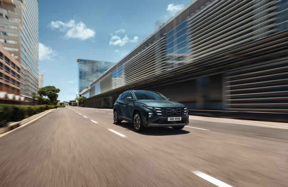 New Hyundai TUCSON driving at speed down a city street.