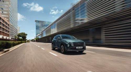 New Hyundai TUCSON driving at speed down a city street.