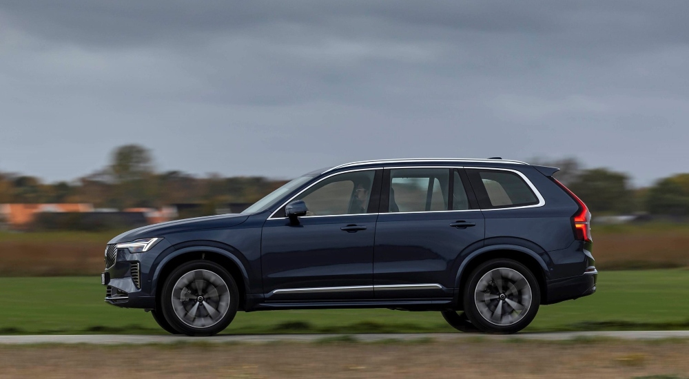 Side view of a Volvo XC90 Plug-in Hybrid driving down a road; Volvo XC90 Plug-in Hybrid used car for sale