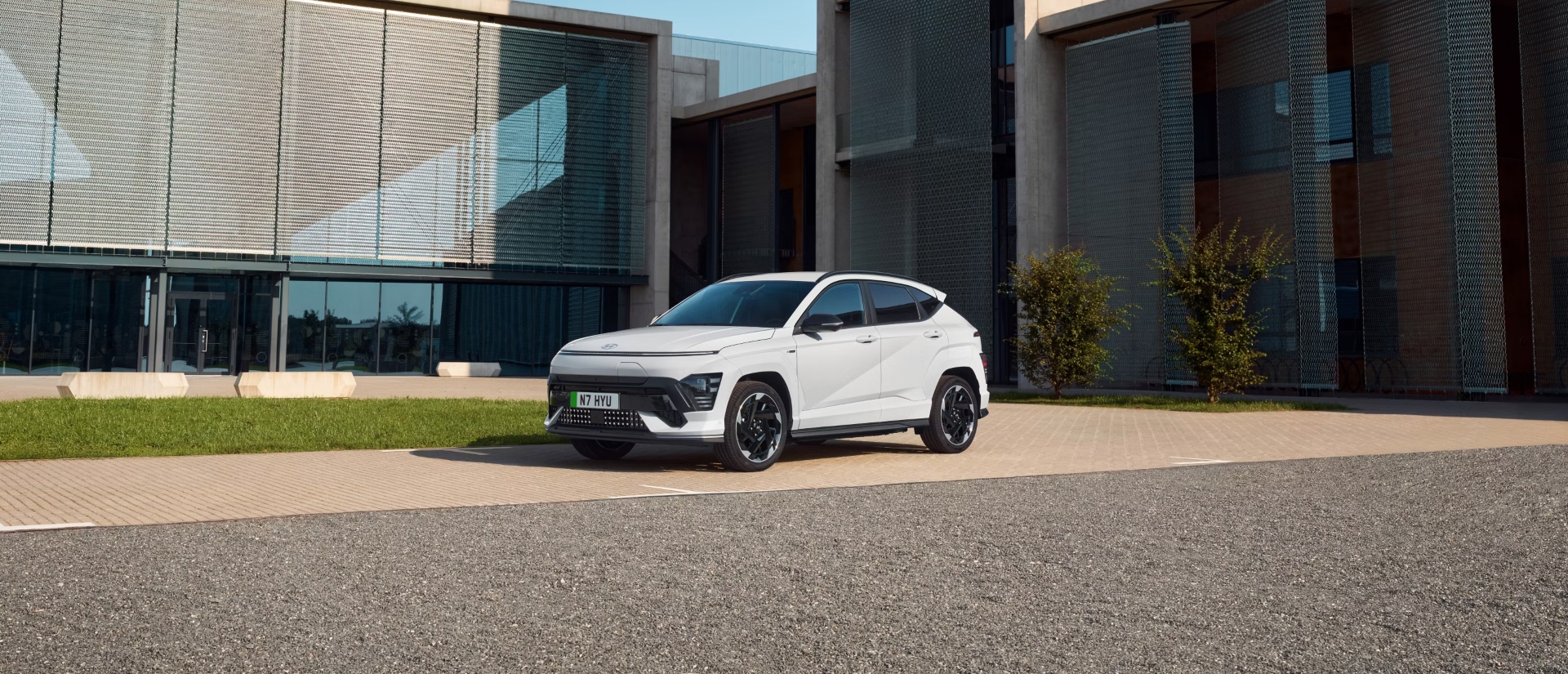 Angled shot of a white Hyundai KONA Electric parked outside a modern house.