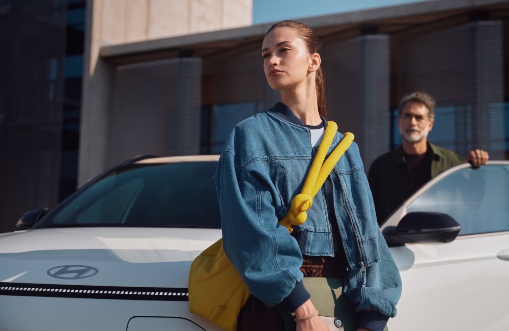 Two people getting out of and standing near a new Hyundai KONA Electric.