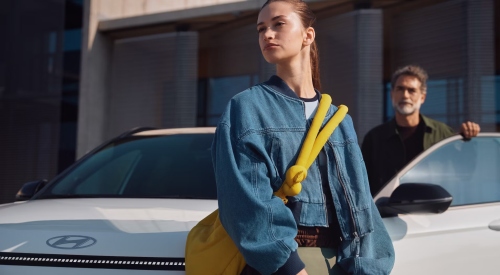 Two people getting out of and standing near a new Hyundai KONA Electric.